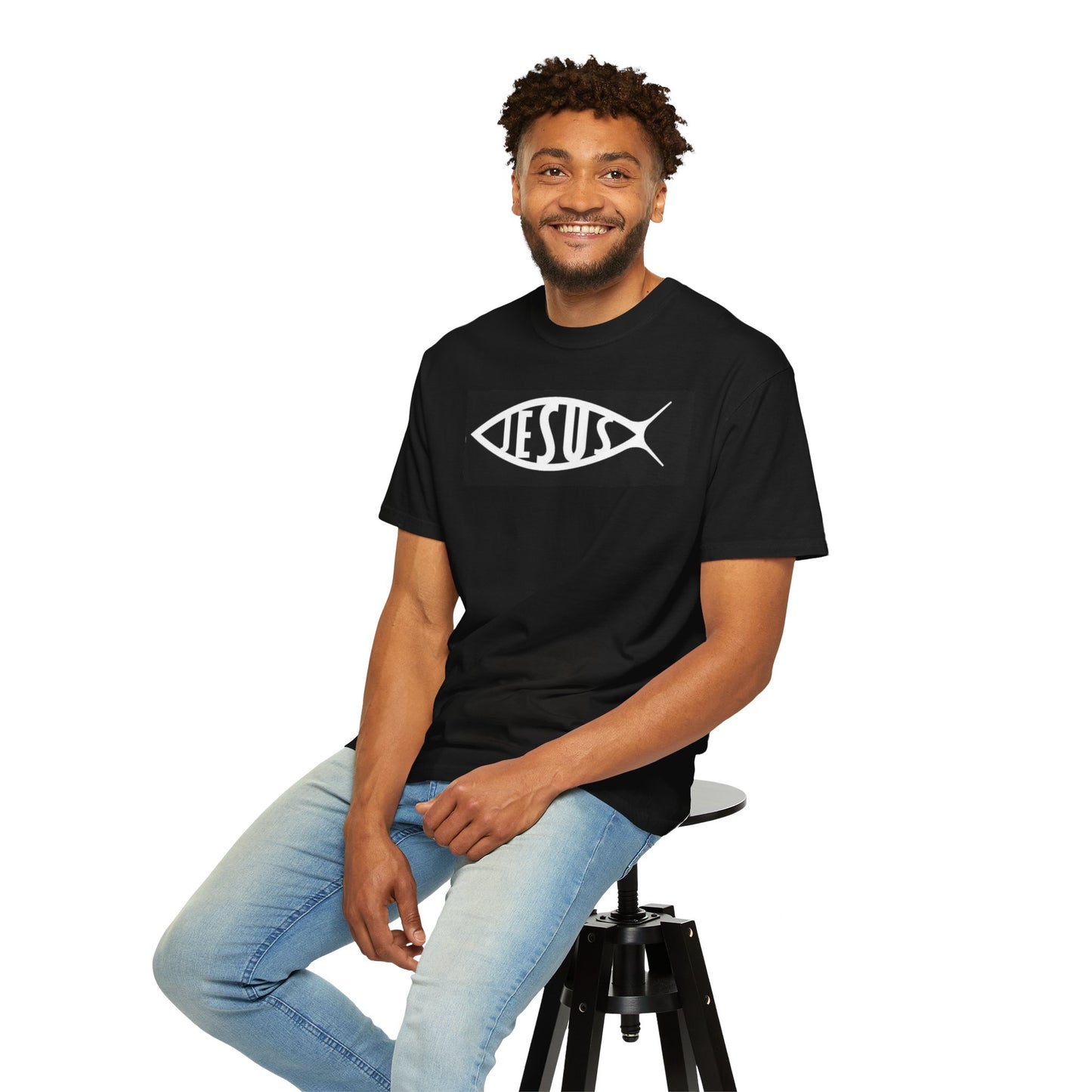 Man wearing a black t-shirt with a fish symbol and 'JESUS' text, sitting on a stool against a white background.