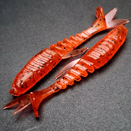 Two red fishing lures with black speckles on a dark gray background