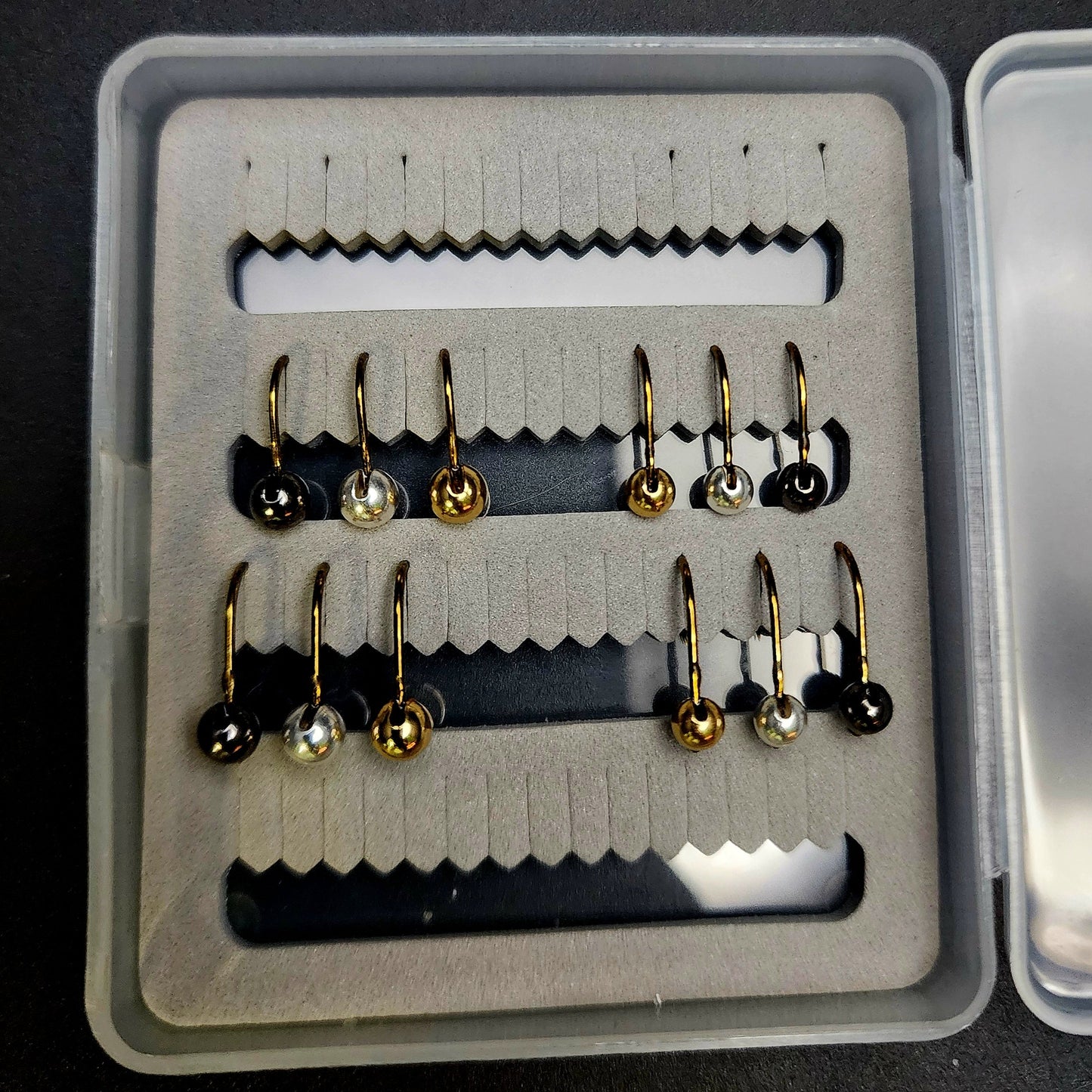 Set of fishing hooks in a box on a black background