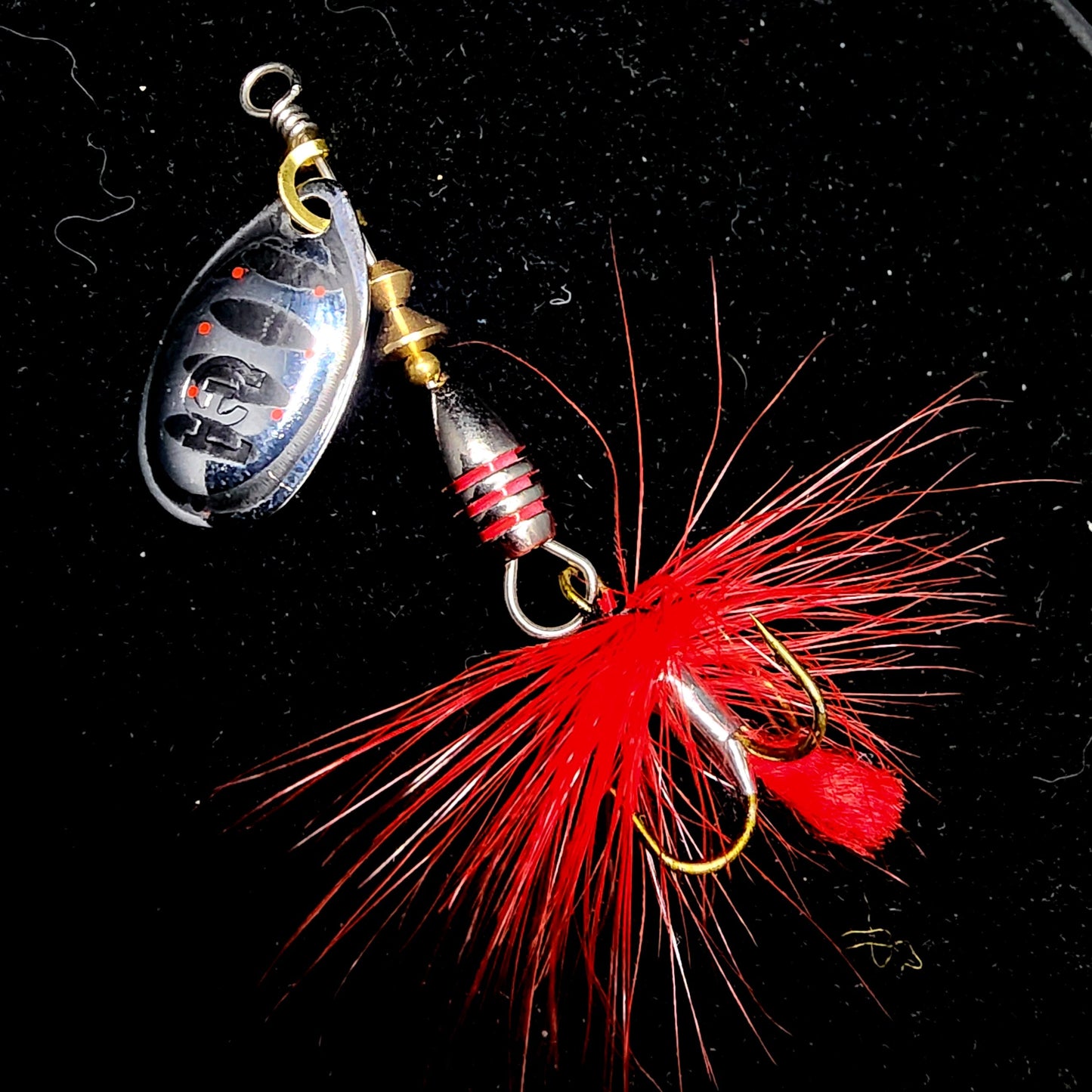 Fishing lure with red feathers on a black background