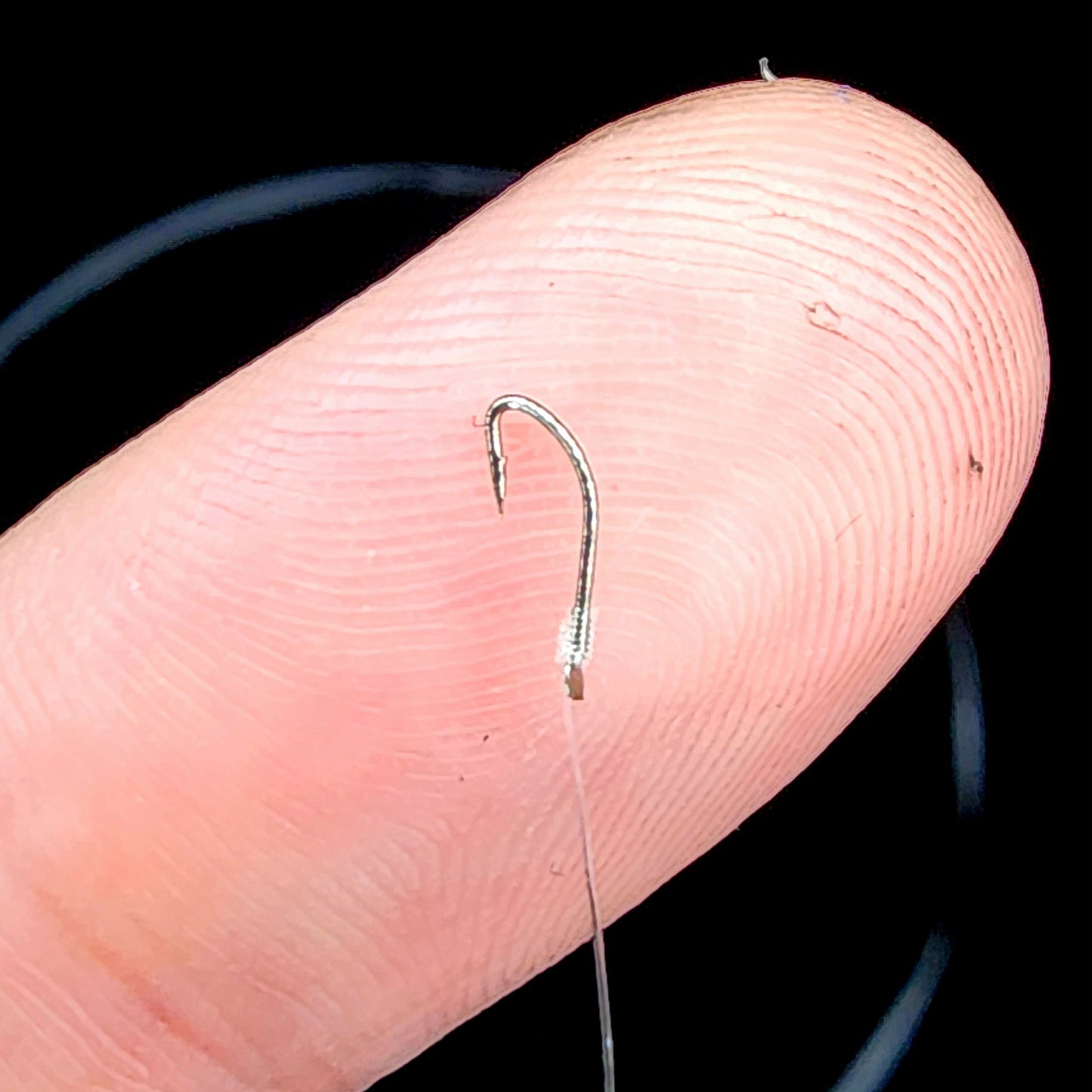 Fishing hook on a finger with a black background