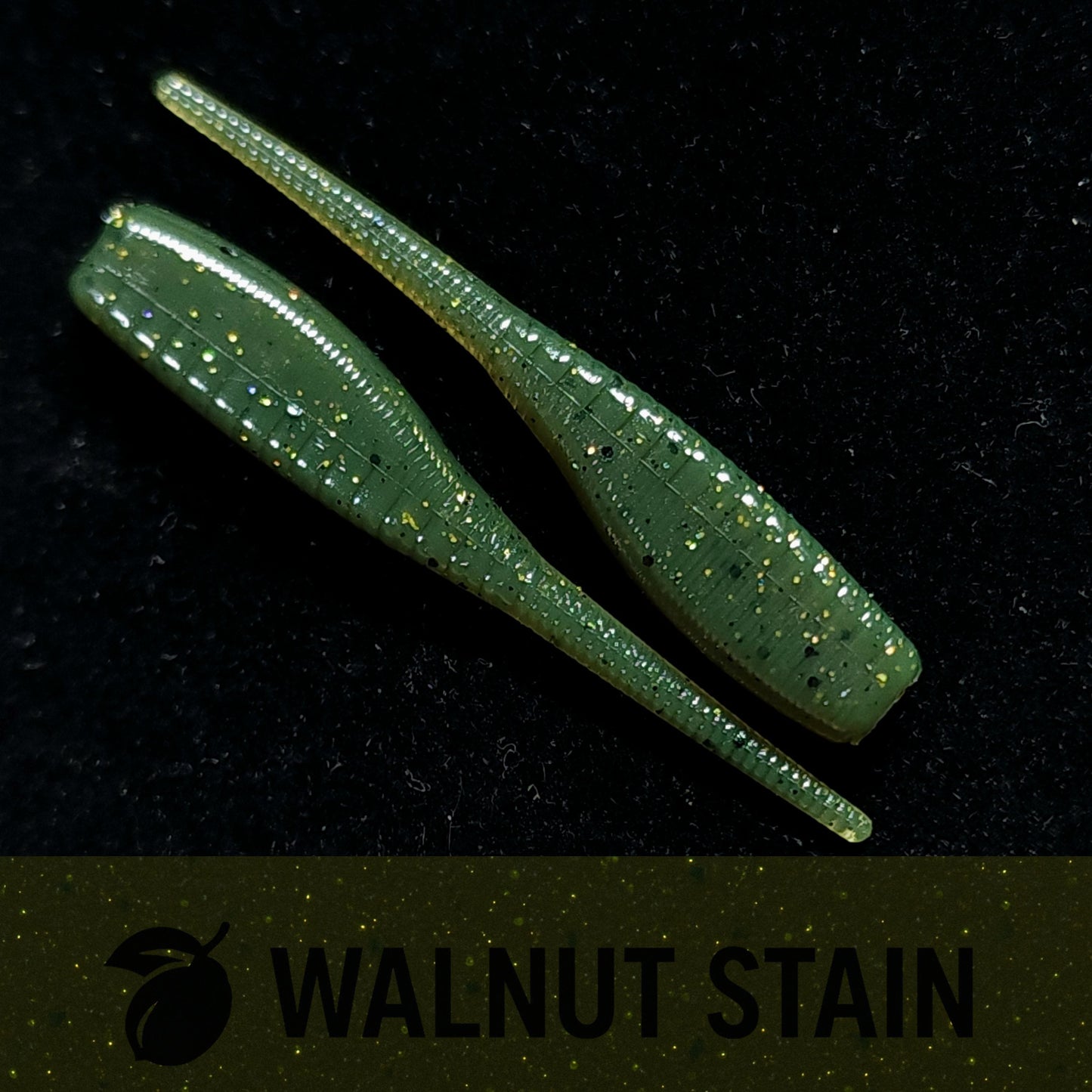 Two green fishing lures with glitter on a black background, labeled 'Walnut Stain'.