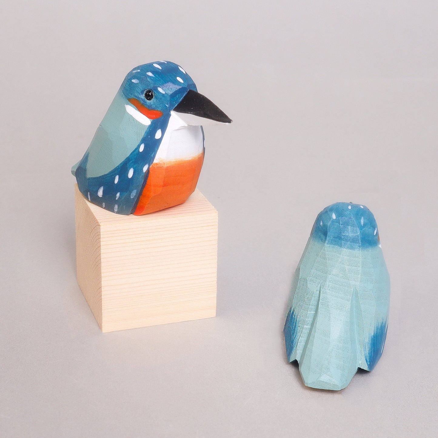 Decorative bird figurine with blue and orange colors on a light gray background