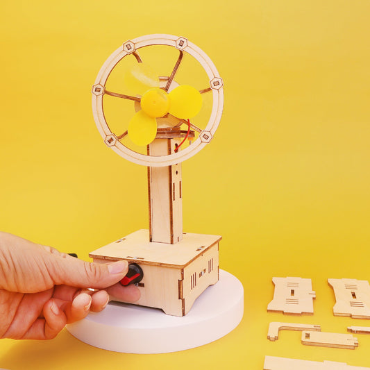 Wooden model of a fan with a hand turning a switch on a yellow background