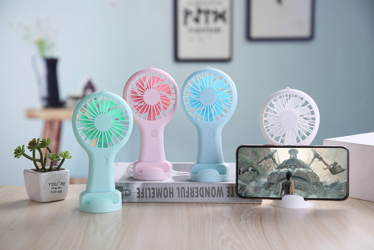 Four colorful handheld fans on a desk with a smartphone displaying a nature scene.