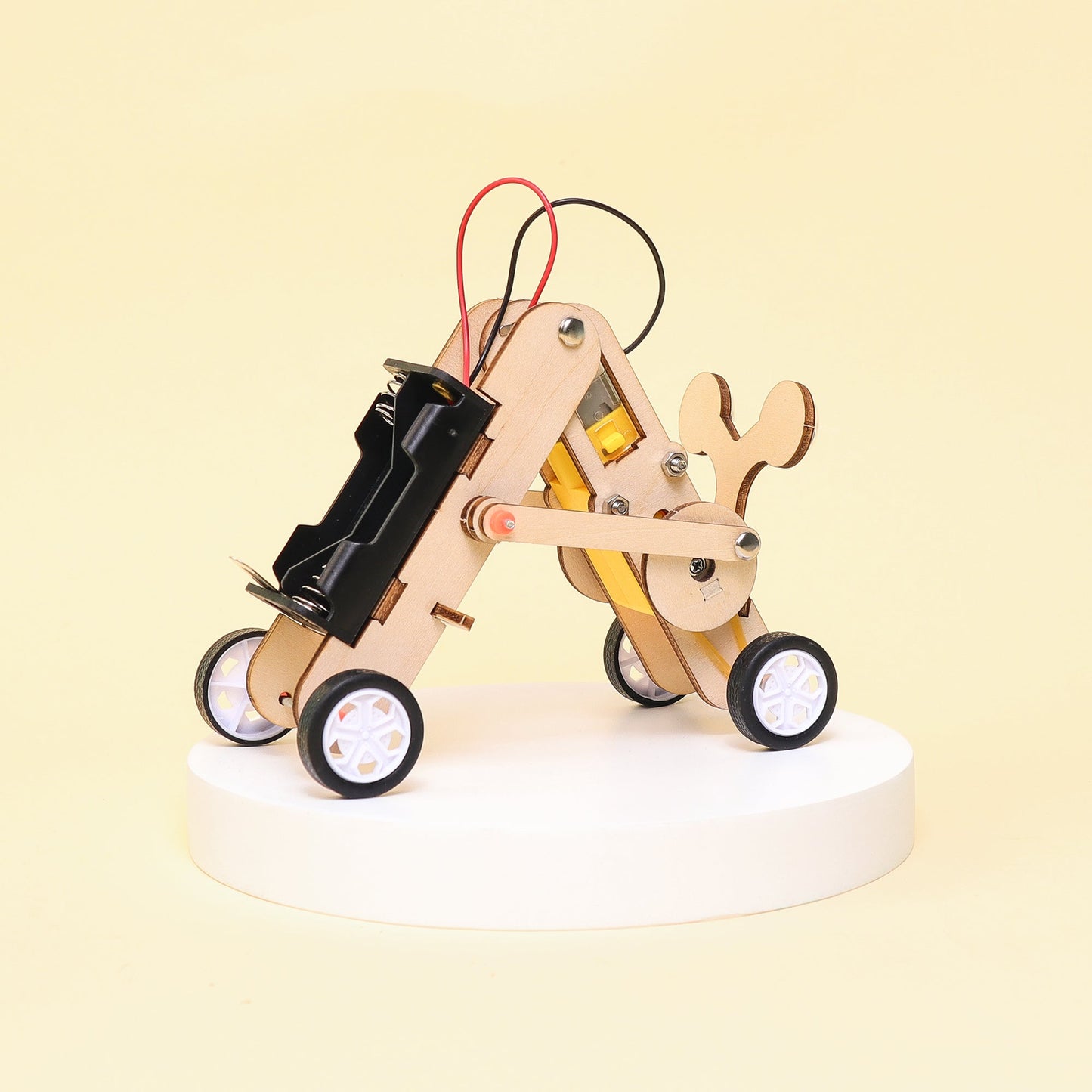 Wooden mechanical model with wheels and electronic components on a light yellow background