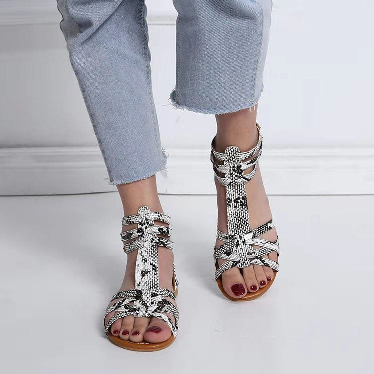 Silver strappy sandals worn with light blue jeans on a white floor.