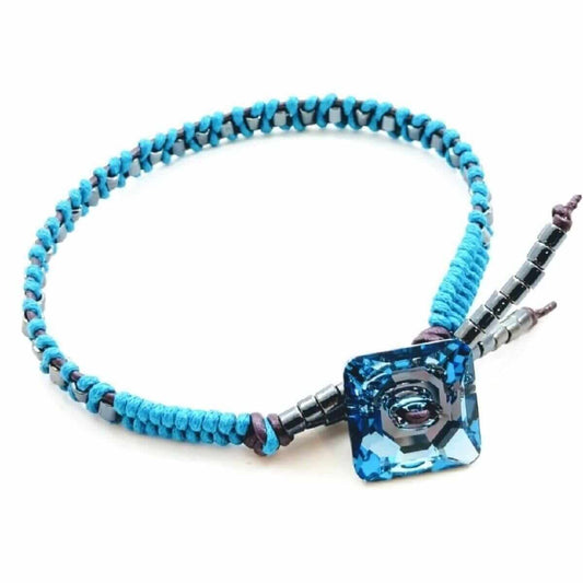 Bracelet with blue beads and a blue crystal pendant on a white background