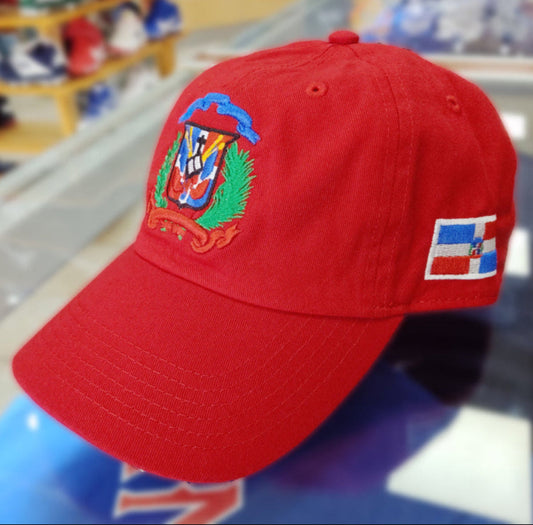 Red cap with a colorful Escudo Republica Dominicana (Dominican Shield) emblem and flag patch on a reflective surface.