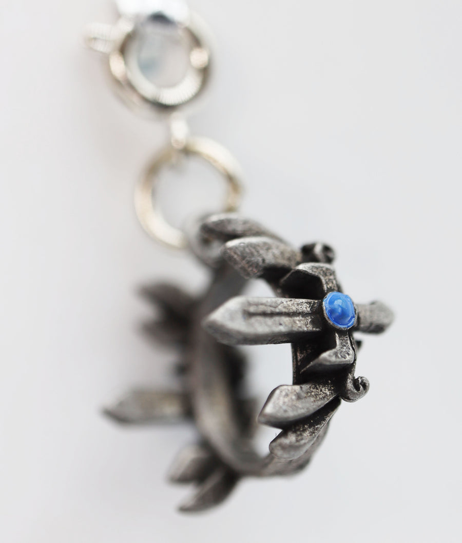 Silver pendant with a blue gemstone on a white background