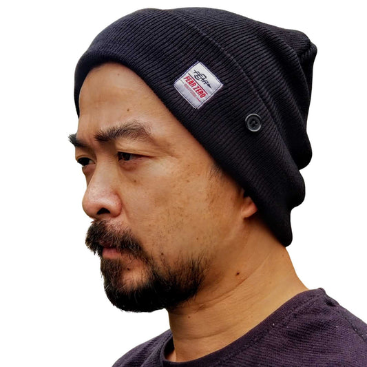 Man wearing a black beanie with a brand logo on a white background