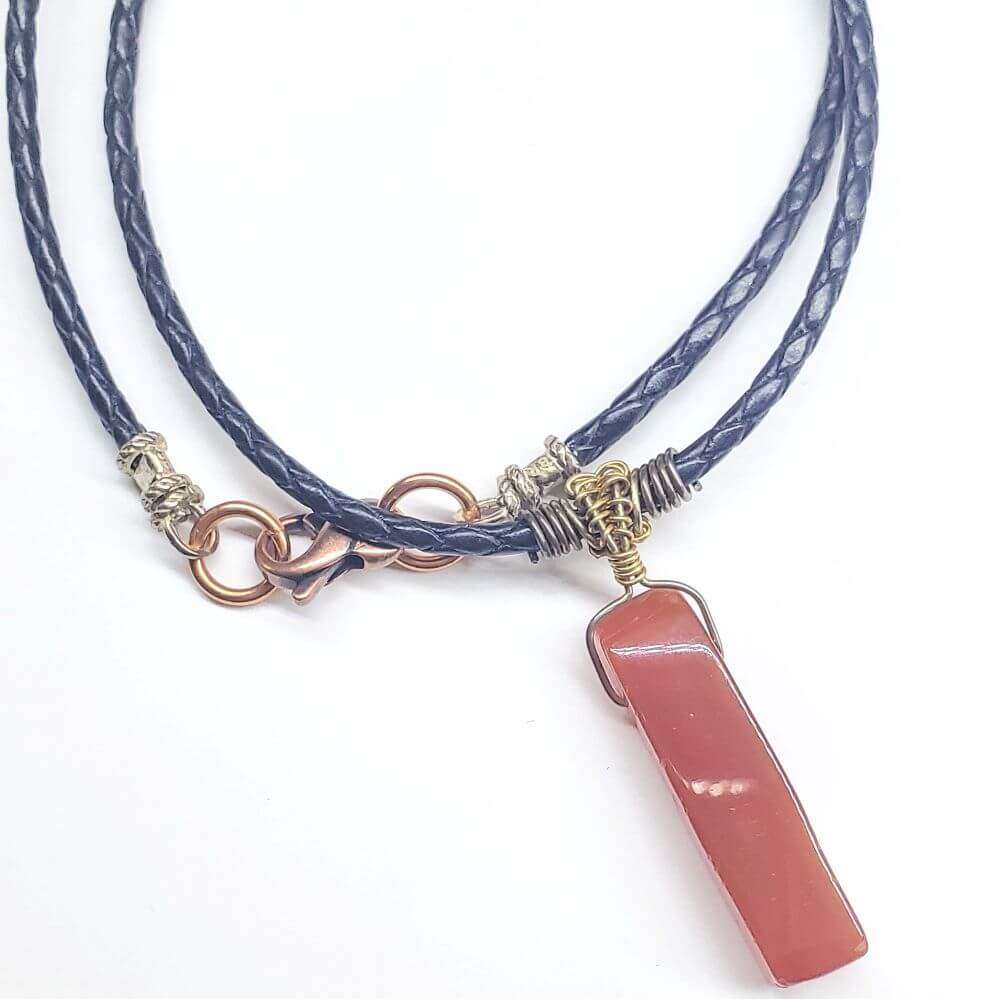 Necklace with blue braided cord and pink stone pendant on a white background