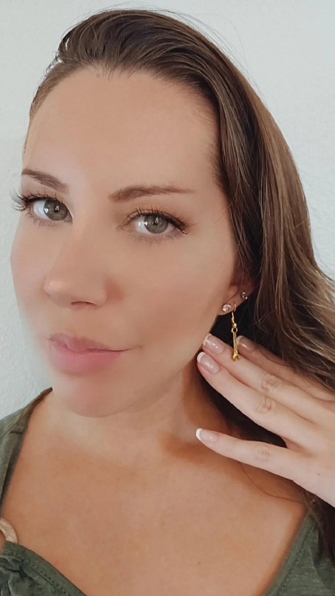 Woman wearing a gold earring with a plain background