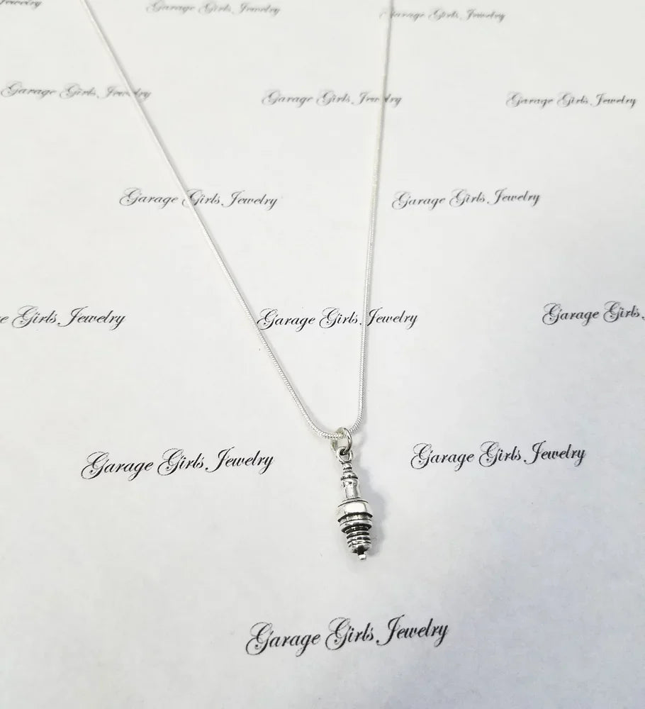 Silver spark plug necklace with a pendant on a white background with 'Garage Girls Jewelry' branding.