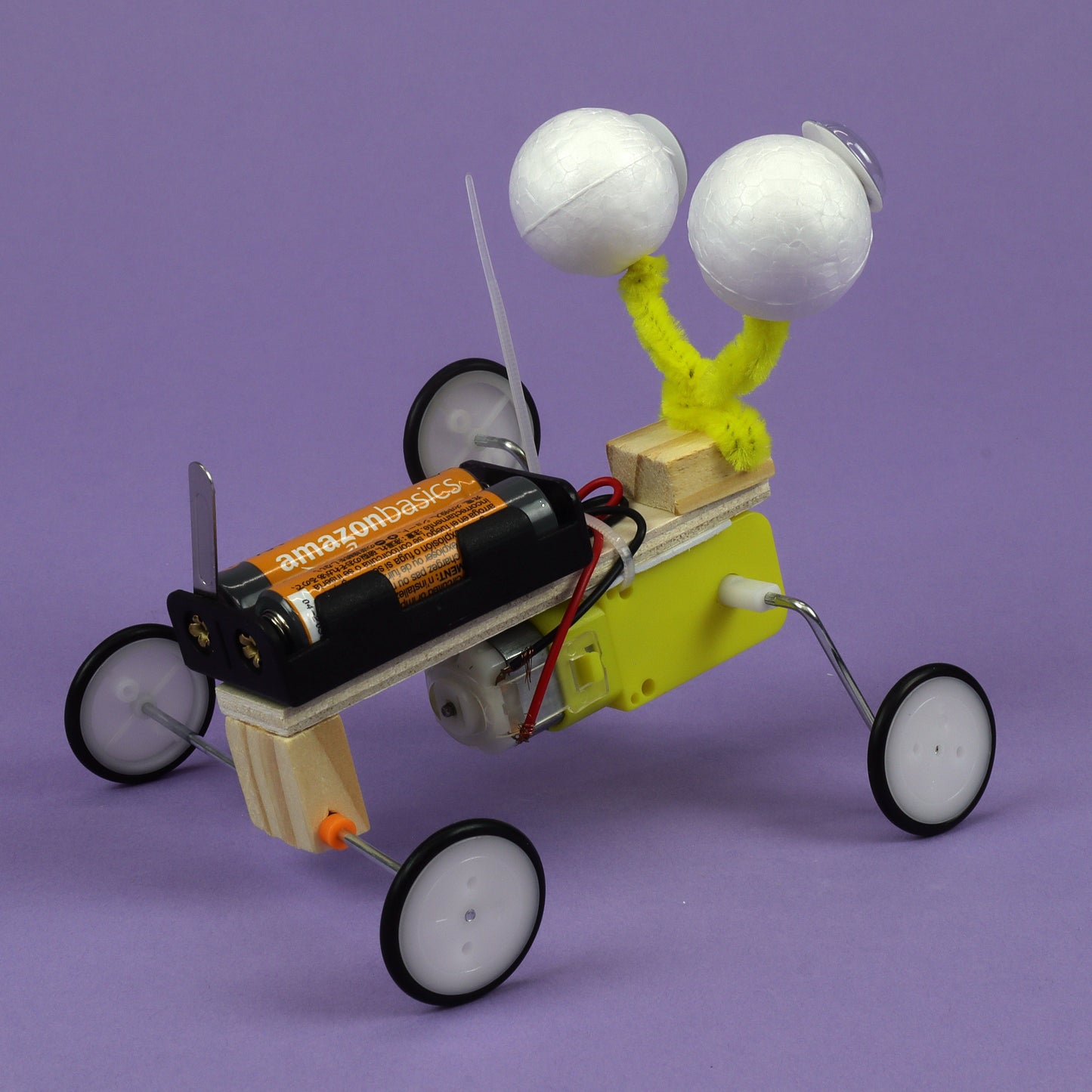Toy car with tennis ball eyes on a purple background