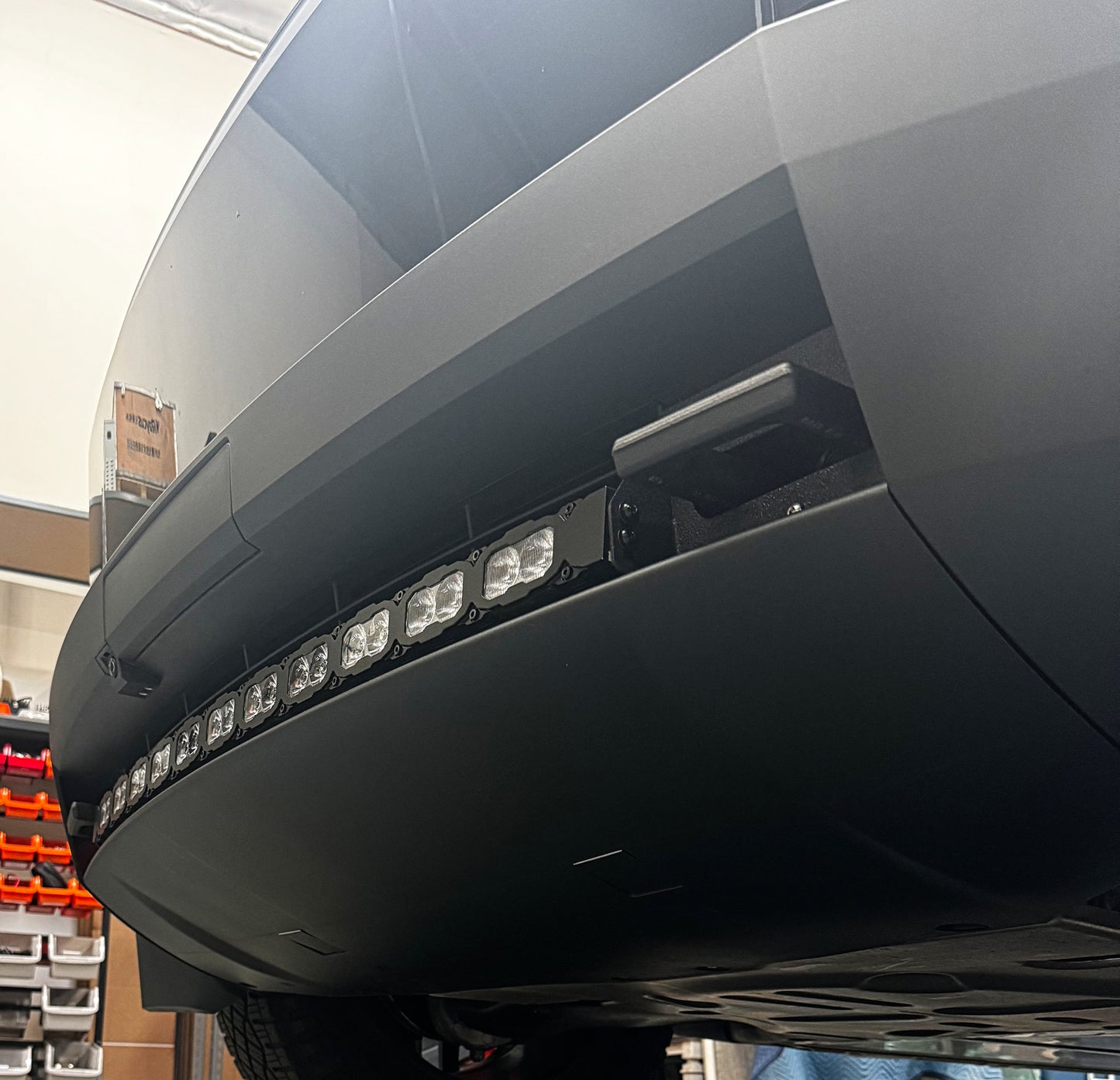 Close-up of a vehicle's front bumper with LED lights in a workshop setting