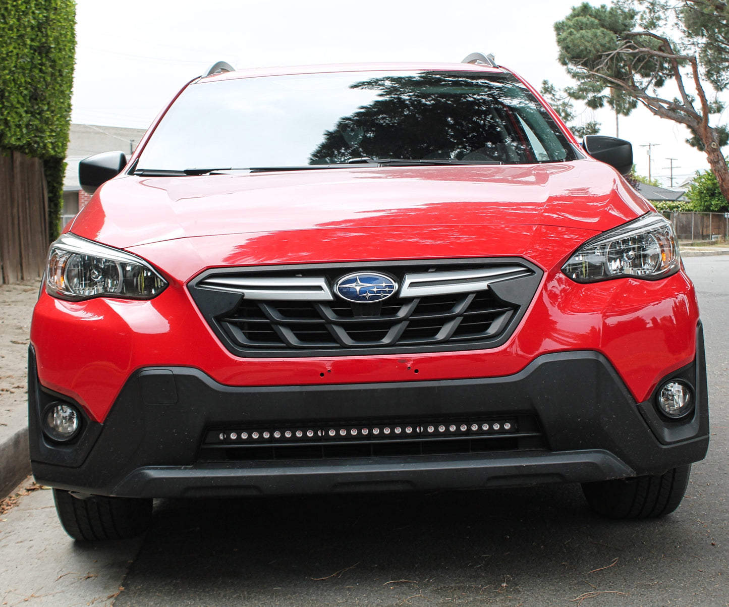 Red Subaru SUV with LED Light Bars parked on a street with trees and houses in the background