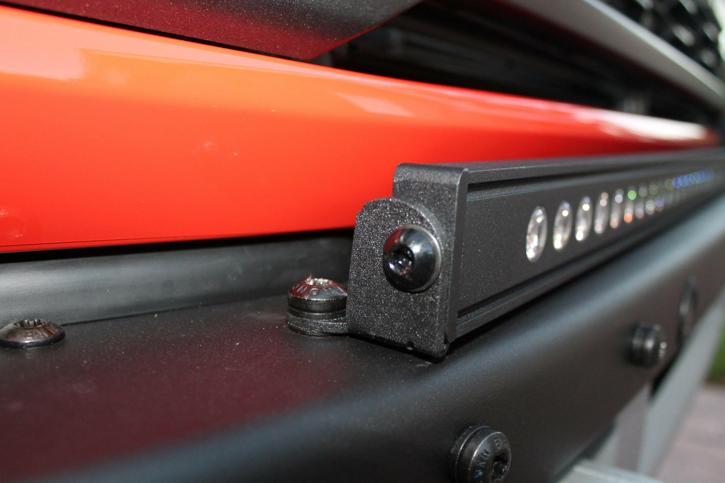 Close-up of a vehicle's black rail system with LED Light Bar on an orange background
