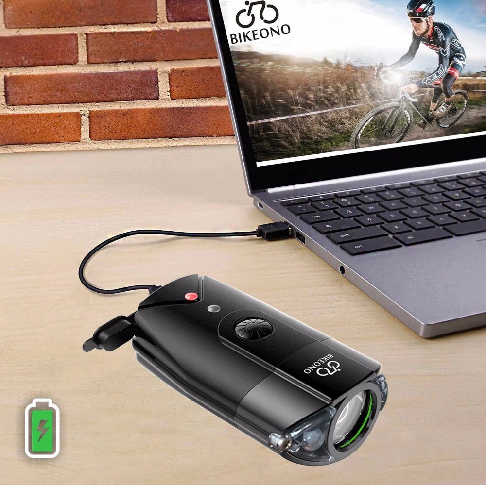 Black flashlight with USB cable connected to a laptop displaying a cyclist on a screen, against a brick wall background.
