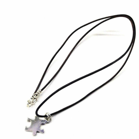 Necklace with a silver puzzle piece pendant on a black cord against a white background
