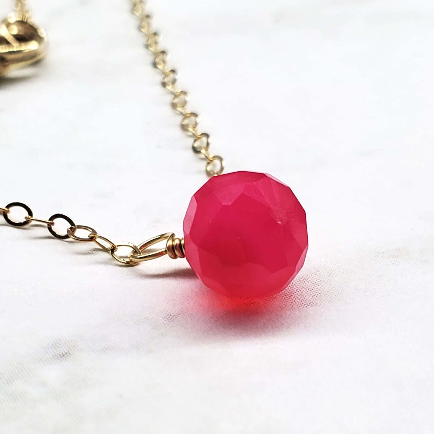 Necklace with a pink bead and gold chain on a white background