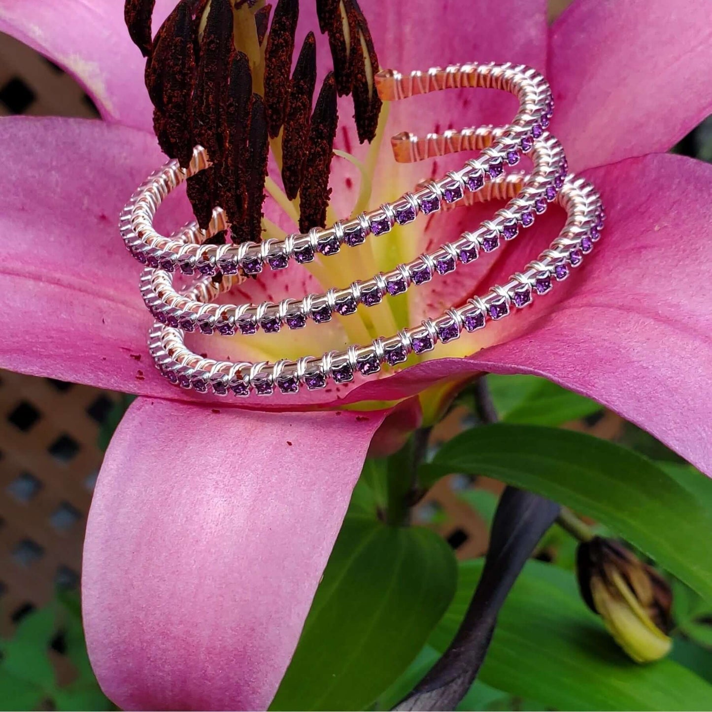 Silver bracelets with purple stones on a pink flower