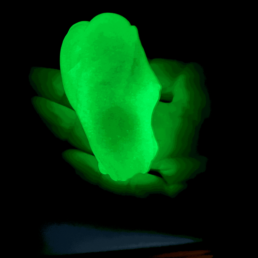 Glowing green gootonium held on a black background