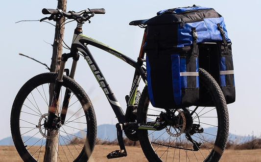 Bicycle with blue panniers attached to a pole against a clear sky.