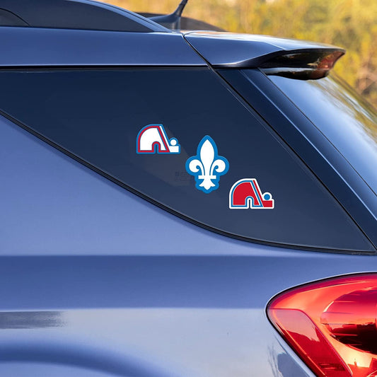 Three decals on a blue car window with a blurred outdoor background