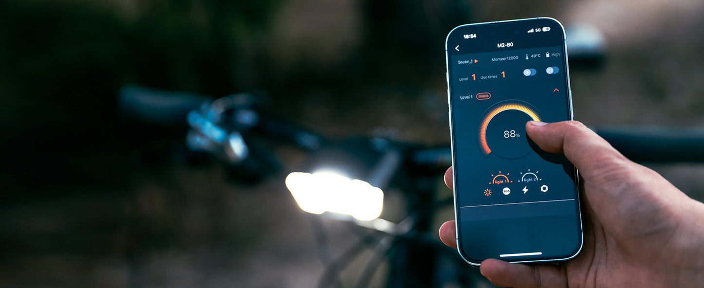 Hand holding a smartphone with cycling app on screen in front of a blurred bicycle