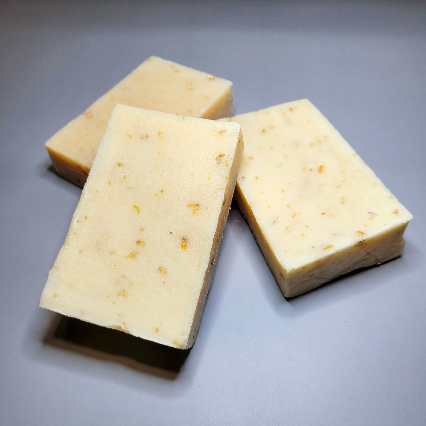 Three blocks of oatmeal soap on a gray background