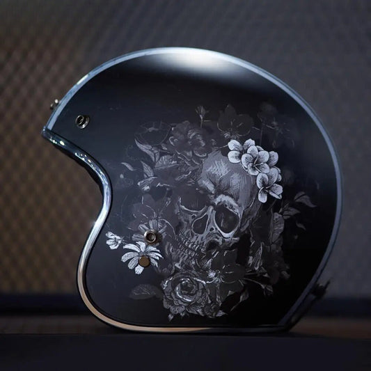 Black motorcycle helmet with skull and floral design on a dark background
