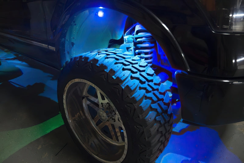 Close-up of a car tire with a blue light illuminating it, on a dark background.