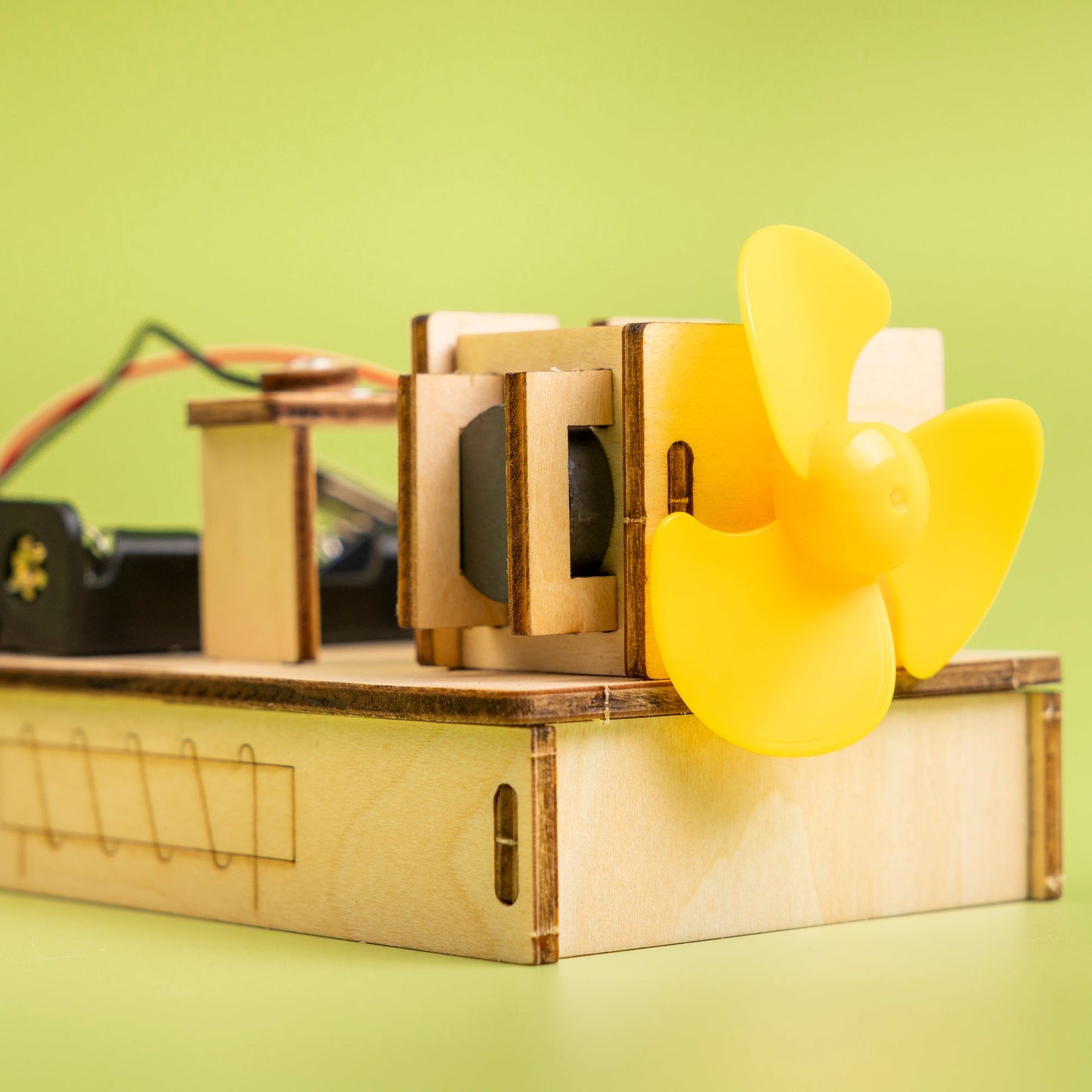 Wooden mechanical model with a yellow propeller on a green background