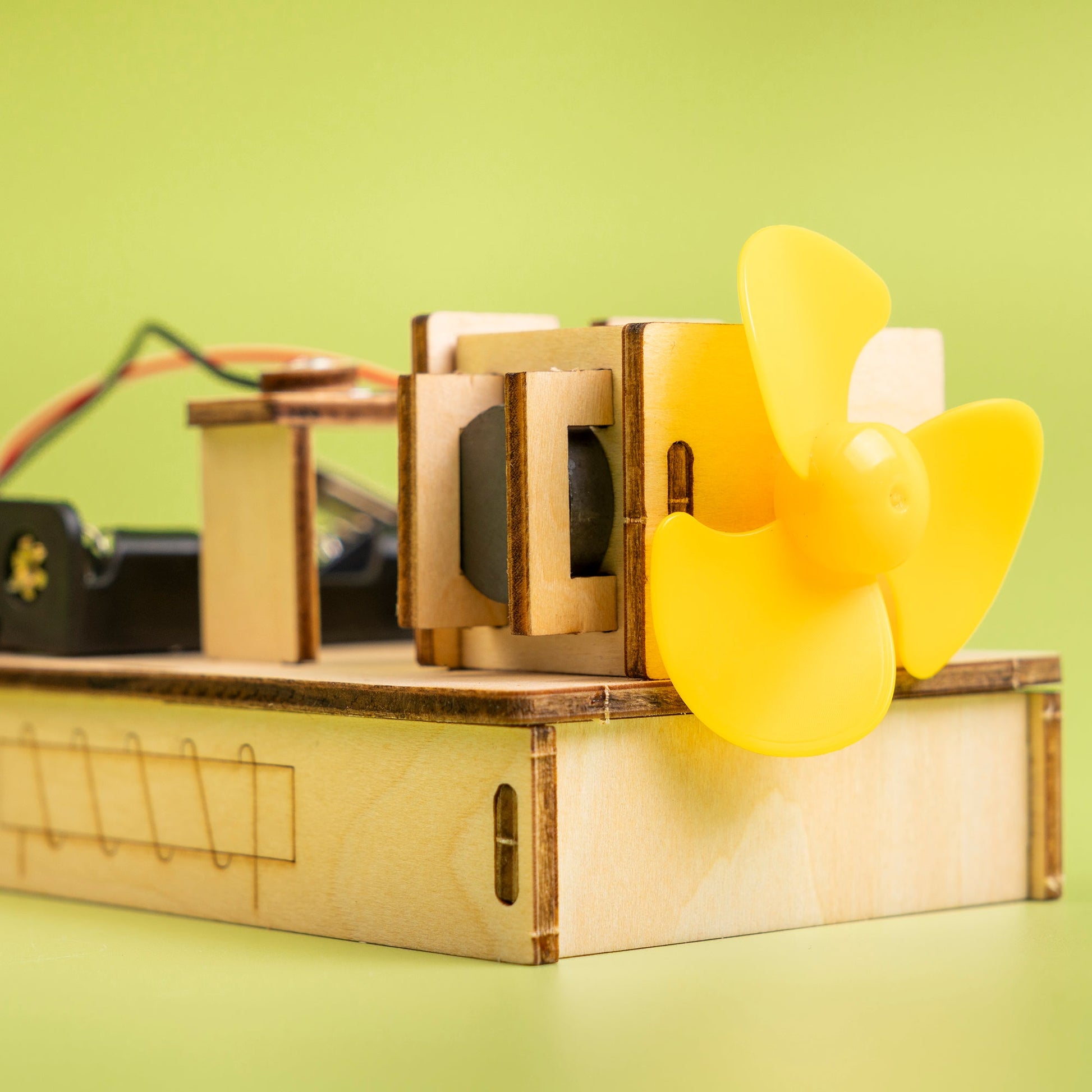 Wooden mechanical model with a yellow propeller on a green background