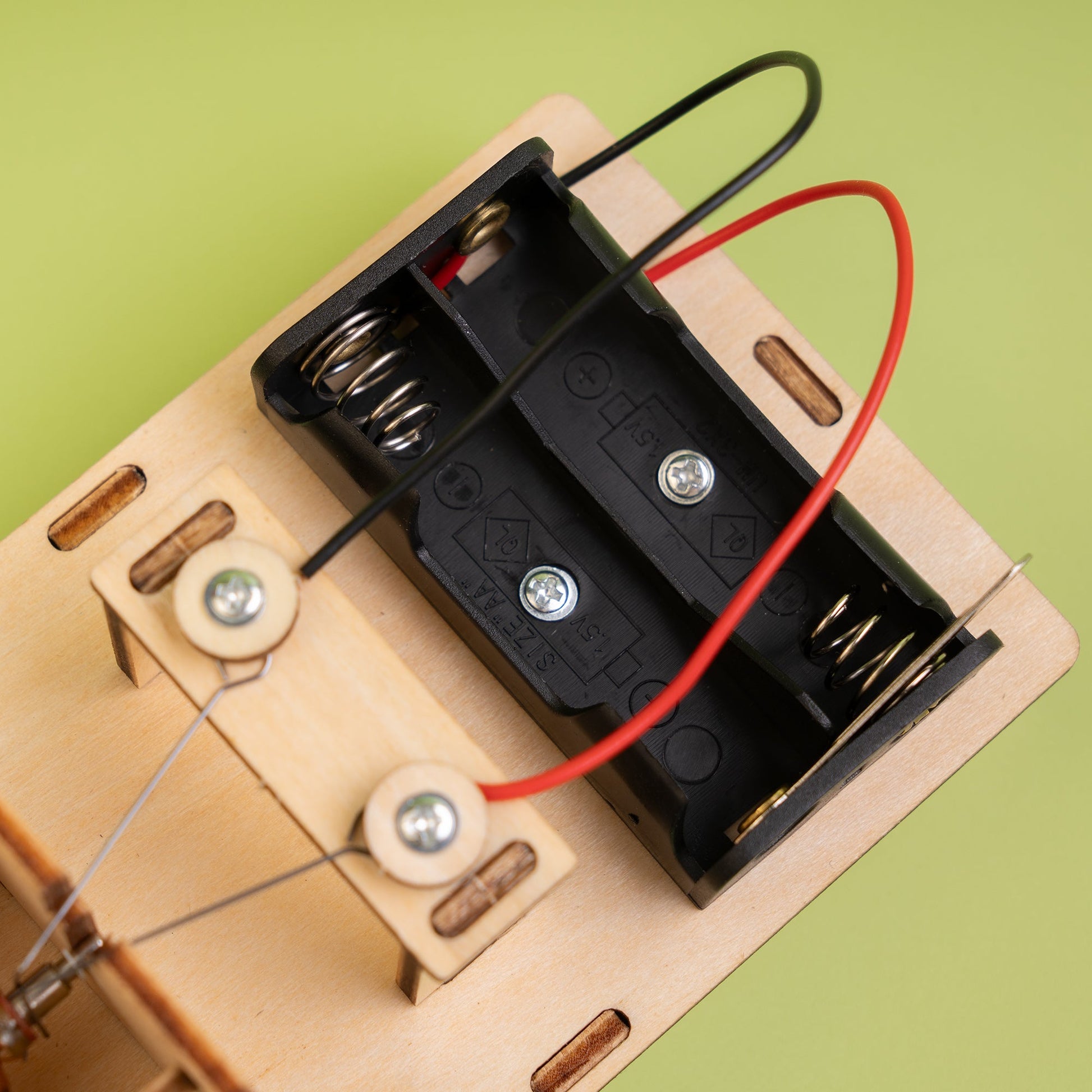 Close-up of a battery holder with wires on a green background
