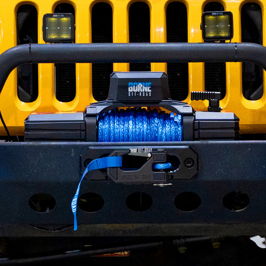 Close-up of a winch on a yellow vehicle bumper with blue lights.