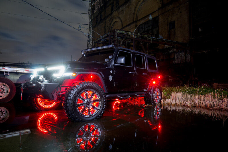 Black off-road vehicle with red underbody lighting on a reflective surface at night.