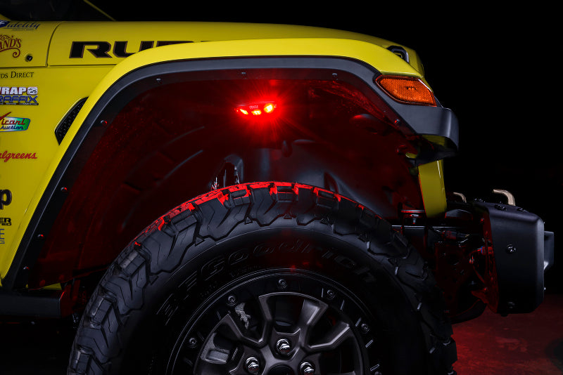 Close-up of a yellow off-road vehicle with a visible tire and red brake light on a dark background.