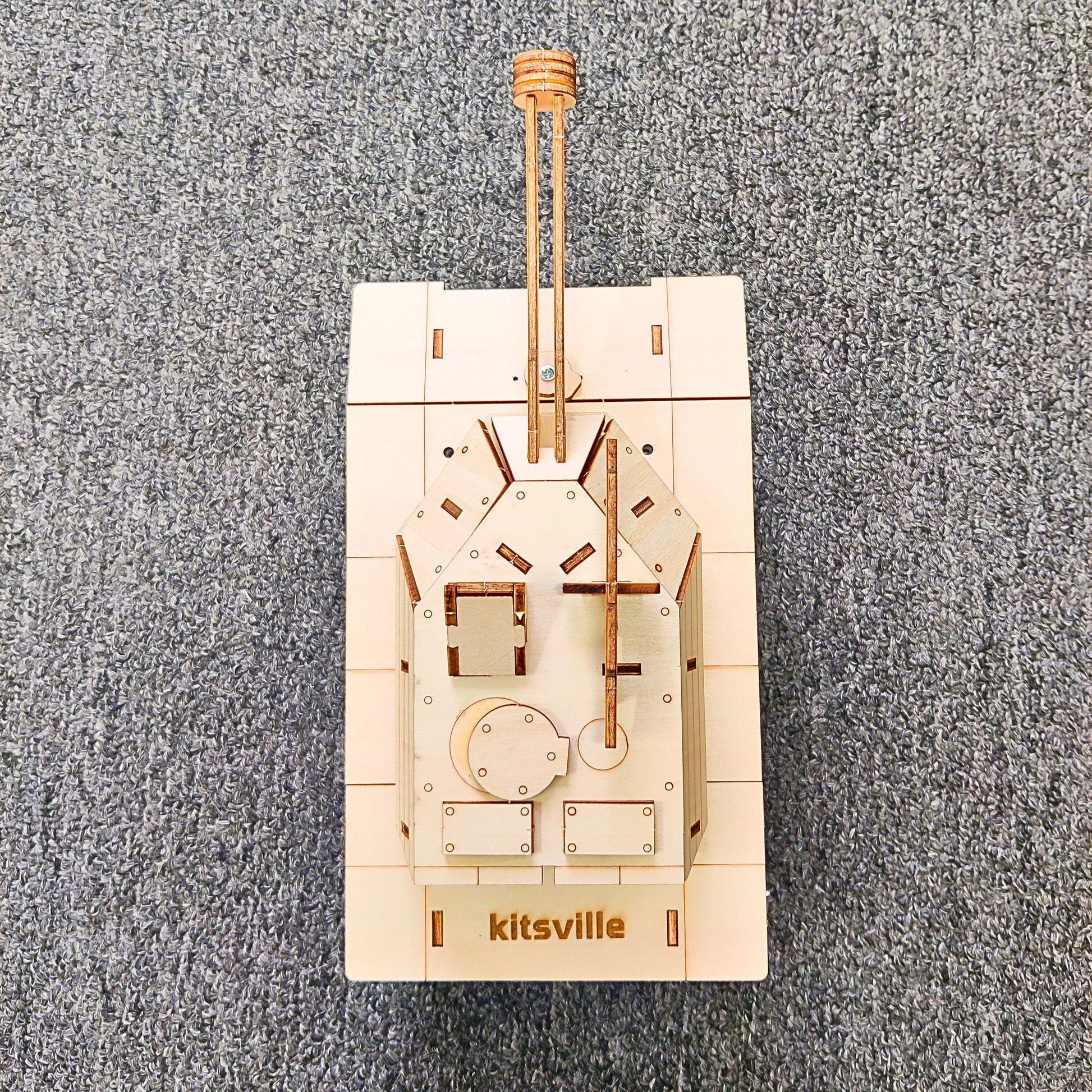 Wooden mechanical model on a gray textured background with 'kitsville' branding.