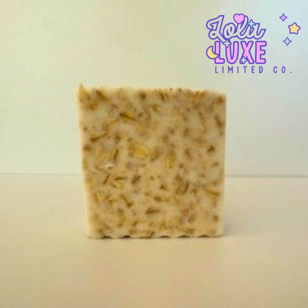 Bar of oatmeal soap with visible ingredients on a light background, featuring the brand 'Loli Luxe'.