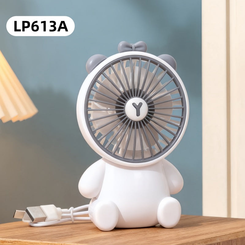 White fan shaped like a bear with gray accents on a wooden surface, against a blurred background.