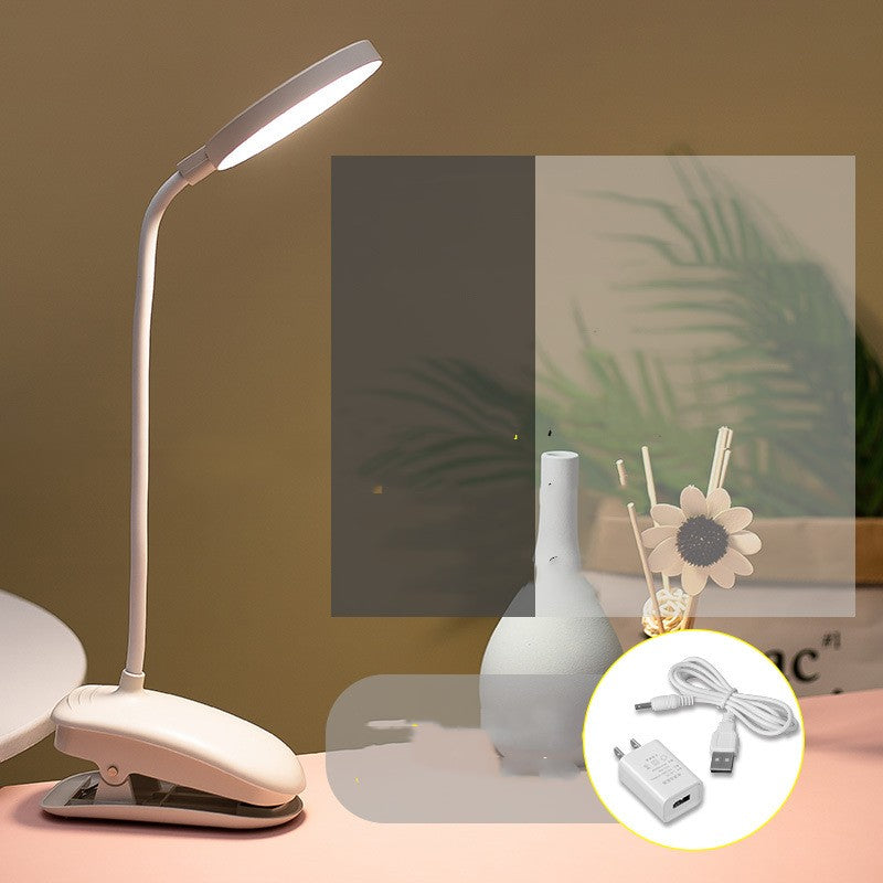 White LED desk lamp with flexible neck on a table, surrounded by decorative items.