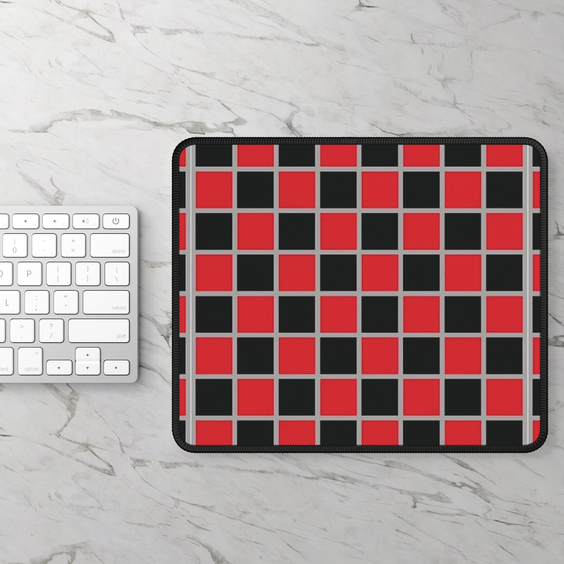 Checkered mouse pad with red and black squares on a marble surface with a keyboard.