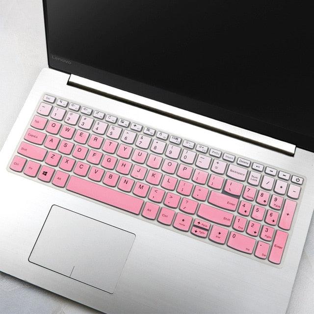 Laptop with a pink keyboard cover on a light gray surface