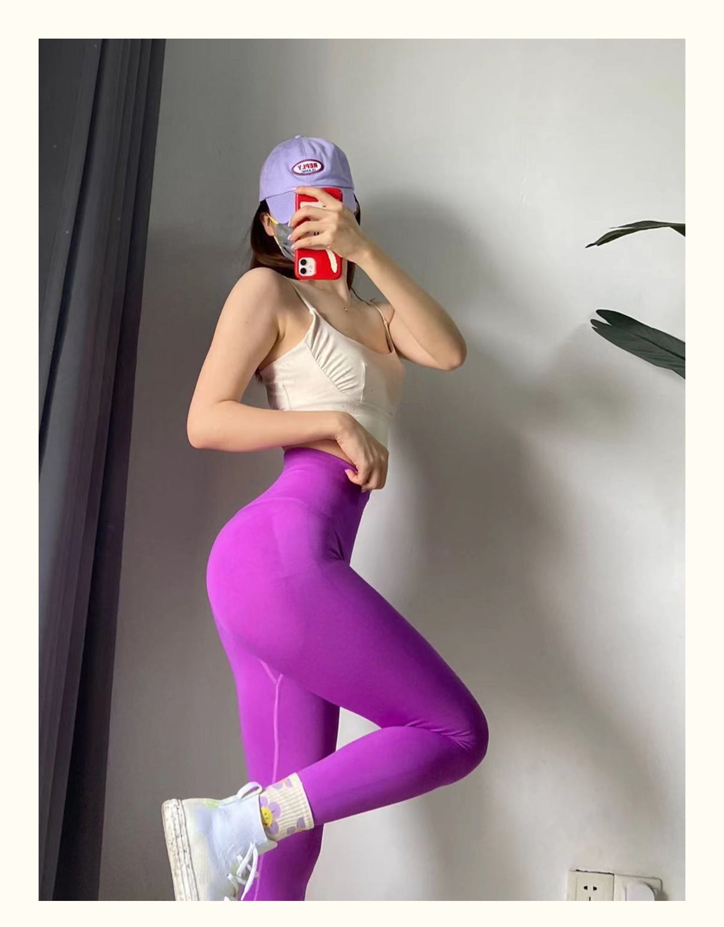 Person wearing a beige top and purple leggings taking a mirror selfie.