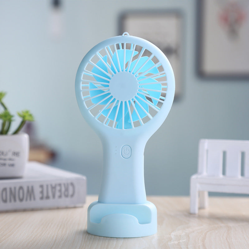 Blue handheld fan on a table with a blurred background