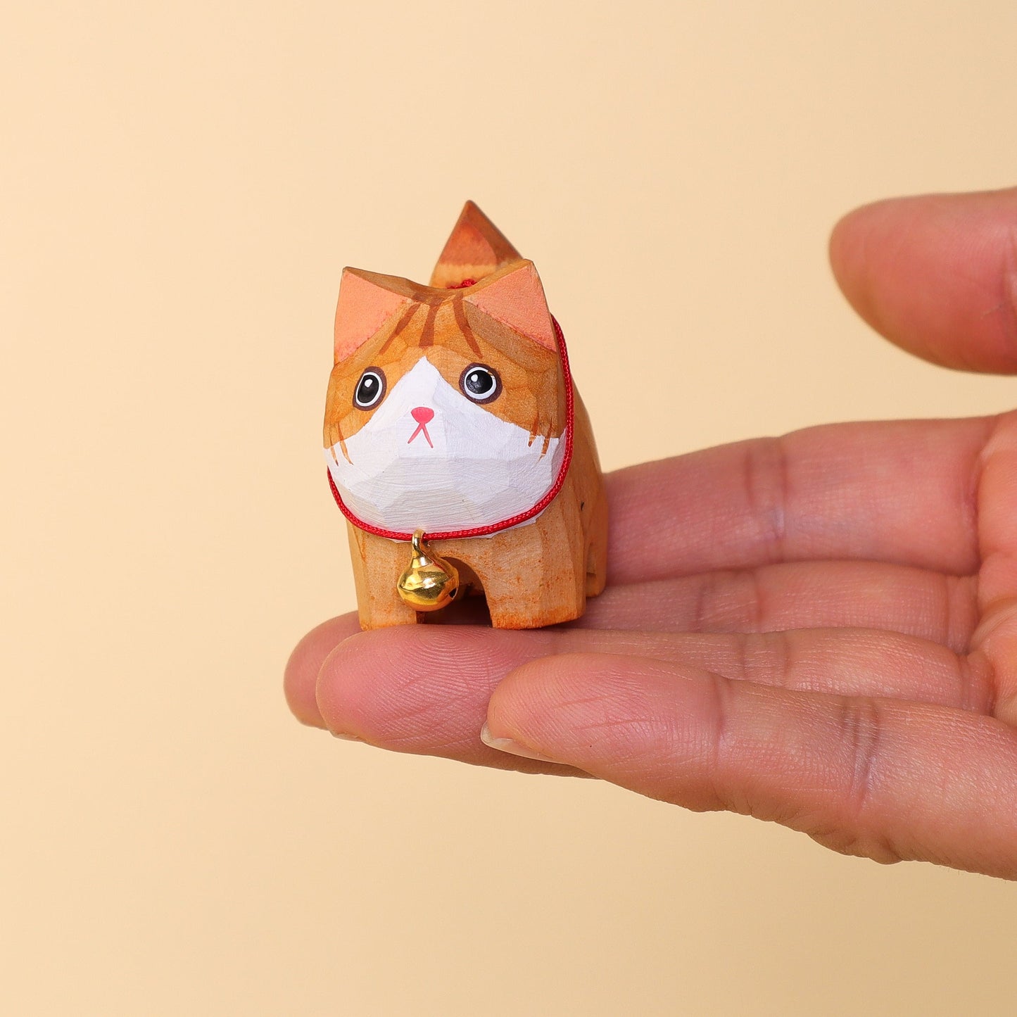 Small cat-shaped figurine held in a hand against a beige background