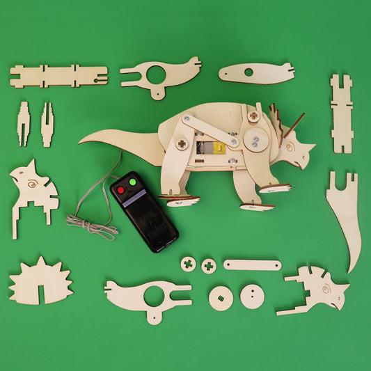 Mechanical dinosaur model kit with components and remote control on a green background