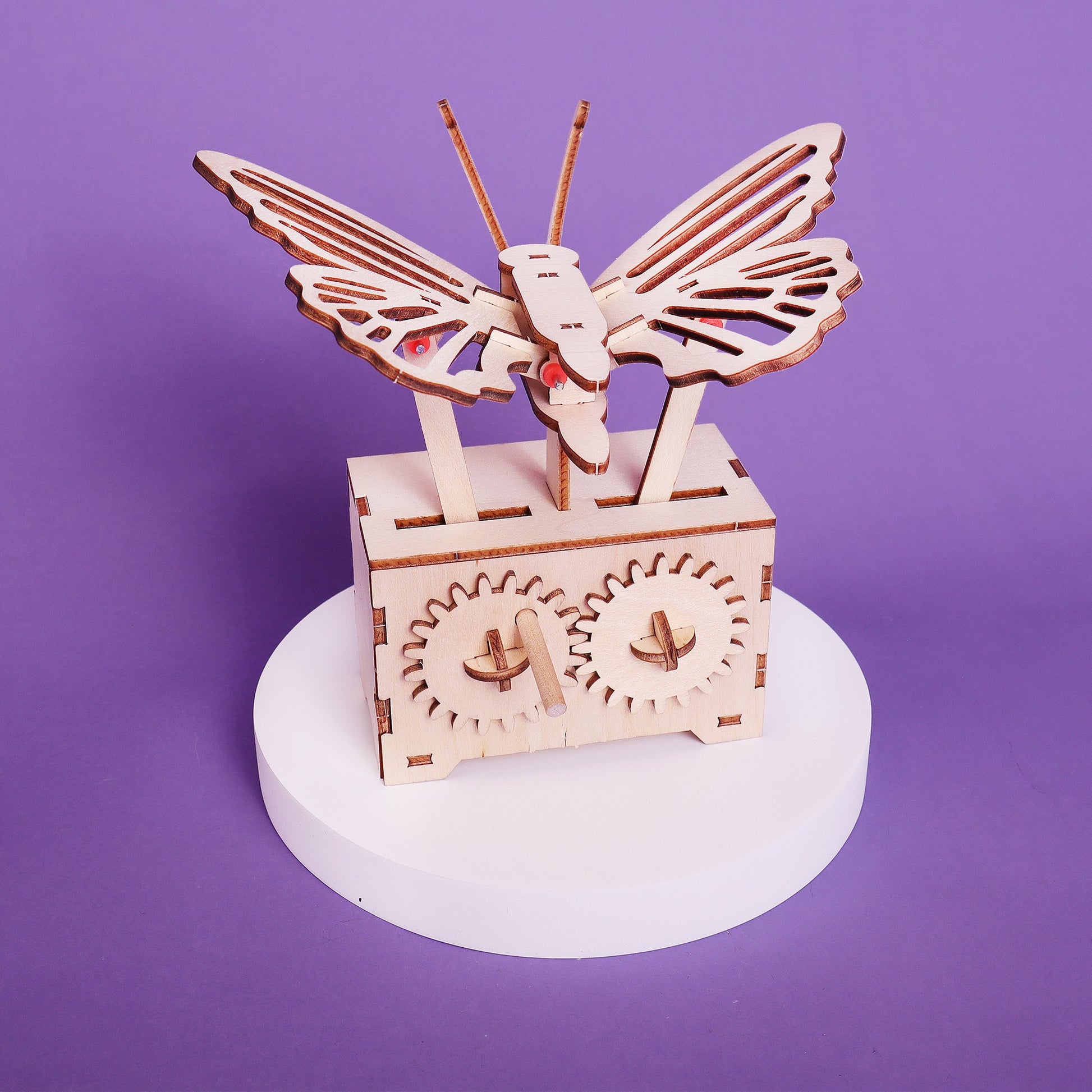Wooden mechanical model of a butterfly on a purple background